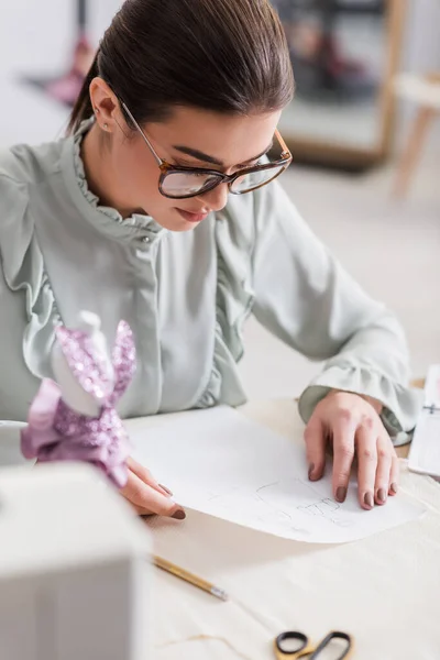 Diseñador Mirando Bocetos Cerca Maniquí Tela Primer Plano Borrosa —  Fotos de Stock