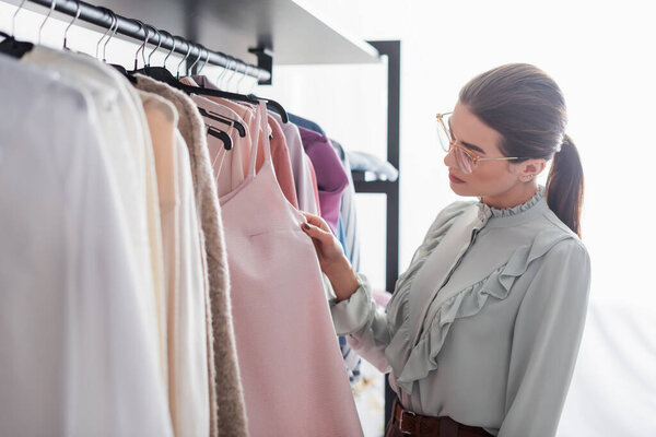 Designer looking at dress on hanger in atelier 