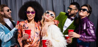 Gri arka planda güneş gözlüklü, ırklar arası eğlenceli arkadaşlar, afiş