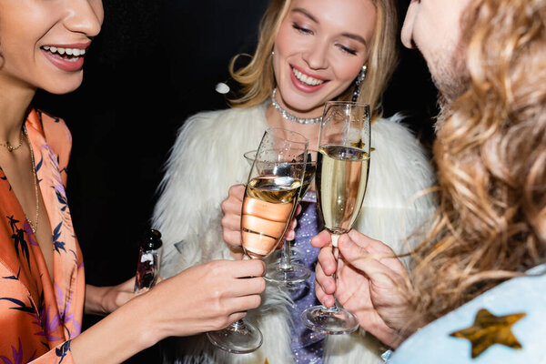 Улыбающиеся взрослые друзья выпивают в ночном клубе на черном фоне