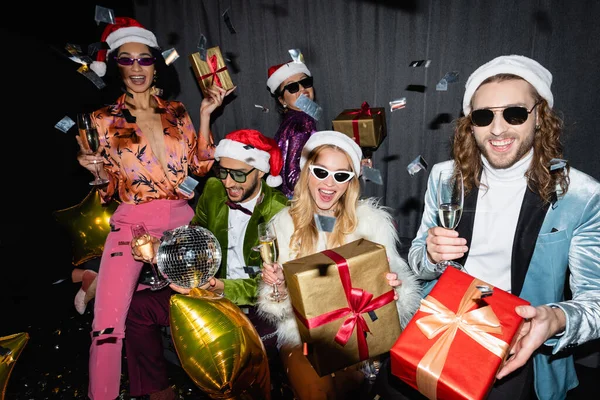 Smiling Interracial Friends Santa Hats Sunglasses Having Party Grey Curtain — Stock Photo, Image