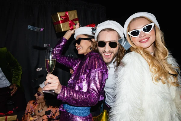 戴着圣诞礼帽的多种族快乐的朋友们 喝着香槟 在灰色的背景下庆祝新年 — 图库照片