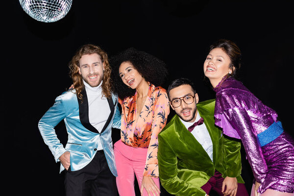 positive interracial friends in colorful clothes having party on black background