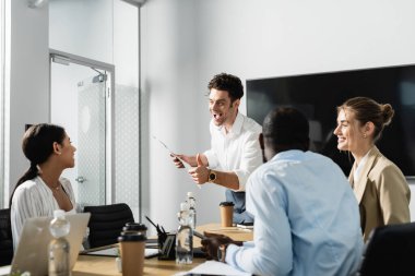 Heyecanlı iş adamı gazetede çok ırklı meslektaşlarını gösteriyor.