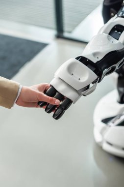 İnsansı robotun elini tutan iş kadınının kısmi görüşü