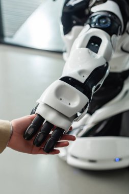 Ofisteki insansı robotun eline dokunan iş kadını görüşü
