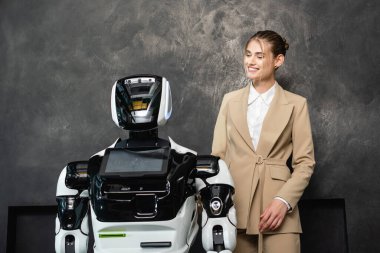 Ofiste robotun yanında duran neşeli iş kadını