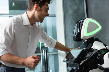 Ofiste robotun yanında duran neşeli iş adamı