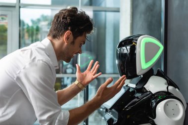 Heyecanlı iş adamı ofisteki insansı robotun yanında hareket gösteriyor.