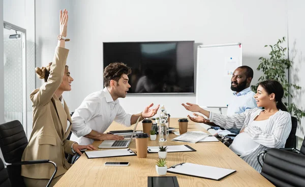 excited multiethnic business people gesturing during discussion in conference room