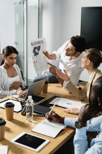 Jovem Empresário Mostrando Jornal Para Colegas Multiétnicos Durante Reunião — Fotografia de Stock