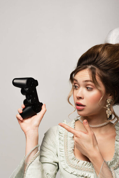 КИЕВ, УКРАИНА - 22 апреля 2021 года: женщина в стиле ретро указывает на джойстик, изолированный на сером