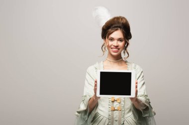 Gri ekranda boş ekranlı dijital tablet gösteren gülümseyen retro tarzı kadın