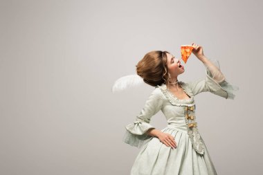 Eski moda giysiler içinde şık bir kadın Gri üzerinde kapalı gözlerle lezzetli pizzalar yiyor.