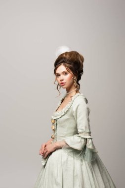 young woman in elegant vintage dress looking at camera isolated on grey clipart