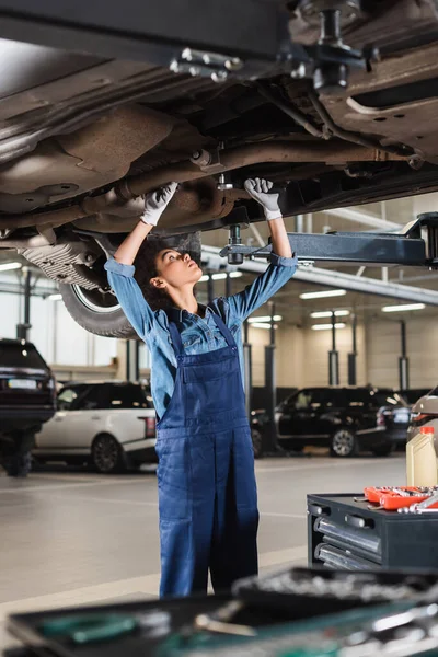 Ung Afrikansk Amerikansk Mekaniker Reparation Bunden Bil Med Skruenøgle Garage - Stock-foto