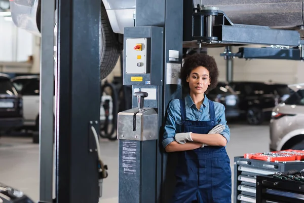 Young African American Mechanic Standing Lifted Car Crossed Arms Looking — Stock Photo, Image