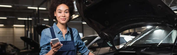 Sonriente Joven Afroamericano Mecánico Pie Con Teléfono Celular Cerca Coche —  Fotos de Stock