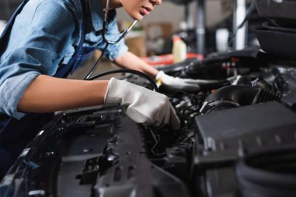 Częściowy Widok Młodego Afrykańskiego Mechanika Rękawiczkach Stetoskopie Pracującego Silnikiem Samochodowym — Zdjęcie stockowe