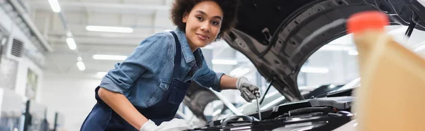 Sonriente Joven Afroamericano Mecánico Sosteniendo Llave Trabajando Con Motor Del —  Fotos de Stock