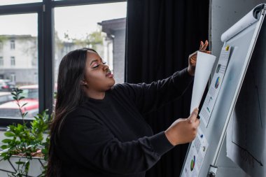 Afro-amerikan artı boyut işkadını grafik ve grafiklere bakıyor.