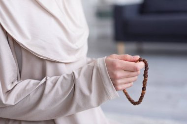 partial view of muslim woman with rosary praying at home clipart