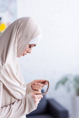 Başörtüsü içinde, evde gözleri kapalı dua eden Arap kadının yan görüntüsü