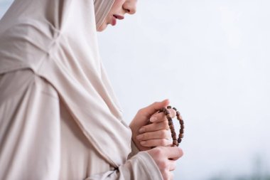 Evde dua ederken elinde tespih tutan genç bir Arap kadının kısmi görüntüsü