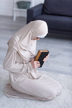 Genç Müslüman kadın evde dua ederken Kuran 'ı tutuyor.