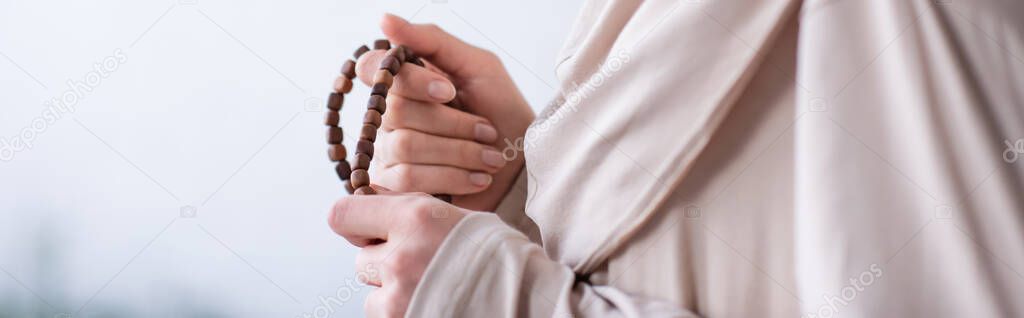 cropped view of muslim woman with rosary praying at home, banner