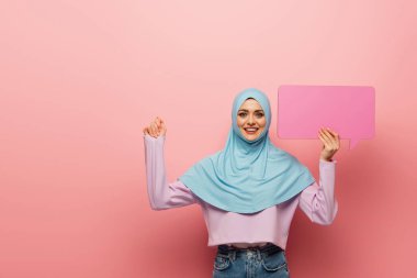 Heyecanlı Müslüman kadın pembe arka planda konuşma baloncuğuyla duruyor