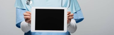 Gri pankartta izole edilmiş boş ekranlı dijital tablet gösteren müslüman doktor görüntüsü