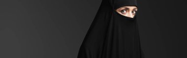 Siyah Niqab 'lı genç Müslüman rahibe siyah pankartta izole edilmiş kameraya bakıyor.