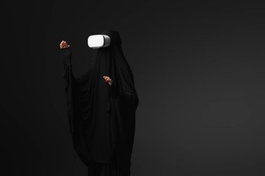 Siyah abaya giymiş Müslüman rahibe, siyah kulaklıkla işaret ediyor.