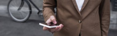 Dışarıda akıllı telefon ve afiş kullanarak resmi giyinen genç işadamlarının kırpılmış görüntüsü