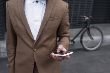 Dışarıda akıllı telefon kullanarak resmi giyinen genç iş adamlarının kırpılmış görüntüsü.