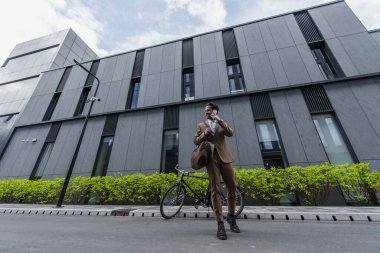 Resmi olarak mutlu genç iş adamları bina yakınında cep telefonuyla konuşuyorlar. 