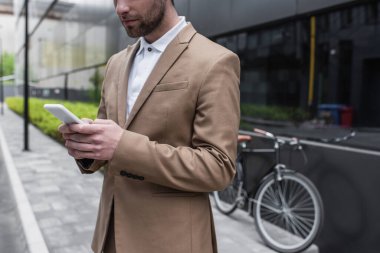 Dışarıda akıllı telefon kullanan sakallı bir iş adamı görüntüsü. 