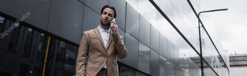 businessman talking on cellphone near building, banner
