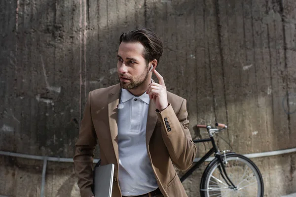 Bearded Businessman Adjusting Earphone Holding Laptop Building — Stock Photo, Image