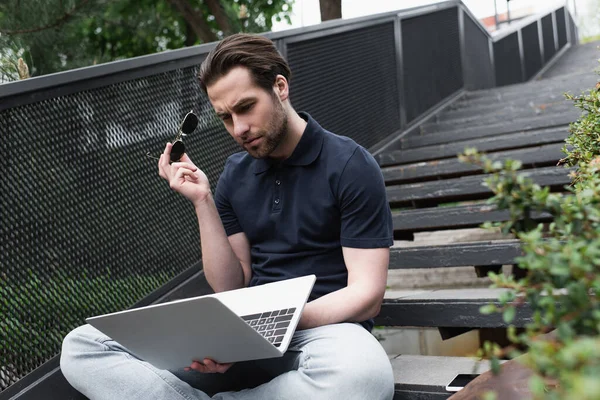 Mann Poloshirt Mit Sonnenbrille Und Blick Auf Laptop Draußen — Stockfoto