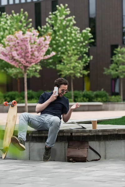 Homem Alegre Óculos Sol Falando Smartphone Perto Longboard Gadgets — Fotografia de Stock