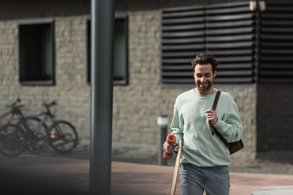 Sonriente Hombre Barbudo Sudadera Sosteniendo Longboard Correa Cuero Mochila Exterior — Foto de Stock