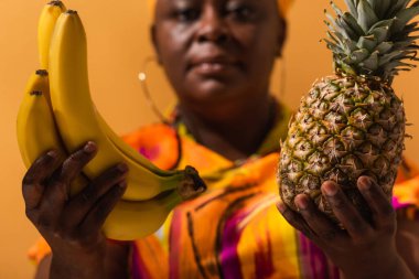 Muz ve ananas bulanık orta yaşlı, turuncu giyinmiş Amerikalı kadının ellerinde.