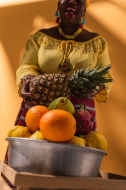 Portakallı ananaslı meyve satan orta yaşlı Afrikalı Amerikalı kadının düşük açılı görüntüsü
