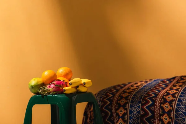 橙子上装饰毛毯旁边凳子上的异国情调水果 — 图库照片