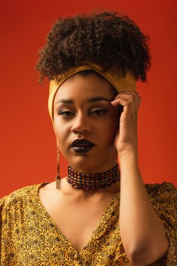 Rujlu genç Afrikalı Amerikalı kadın kameraya bakıyor. Yüzü kızıla yakın.