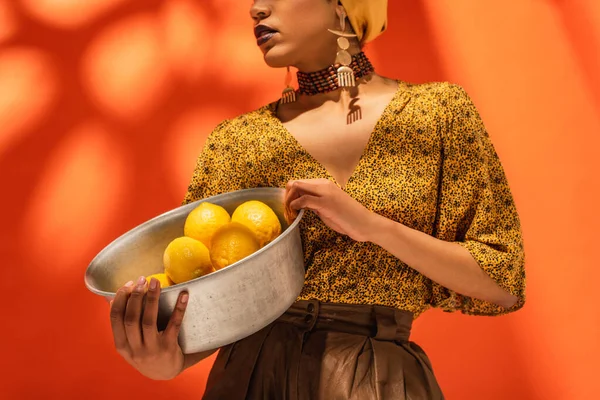 黄色のブラウスにアフリカ系アメリカ人女性の部分的な見解オレンジにレモンと金属製のボウルを保持 — ストック写真