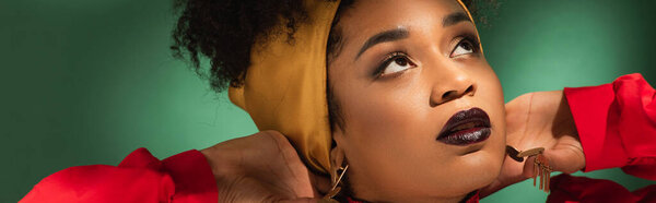 портрет молодой африканской американки с руками возле головы на зеленом, баннер