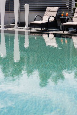 Güverte sandalyelerinin yanında kokteyller ve açık havuz. 